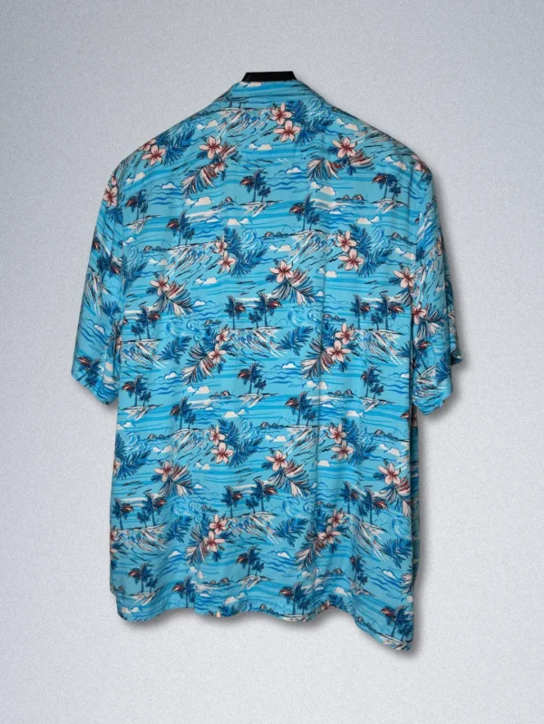 Men's Penguin Tropical Rayon Shirt, a blue short-sleeve button-down with a print of tropical flowers, palm trees, and sailboats.
