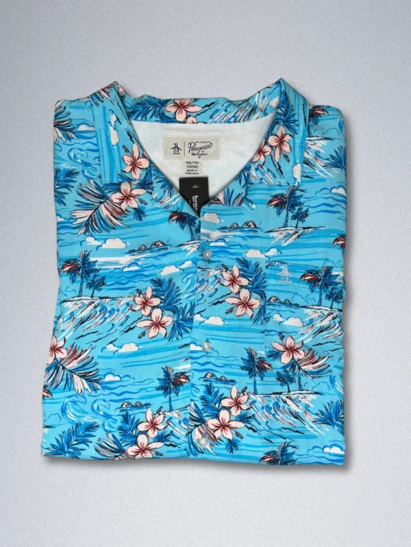 Men's Penguin Tropical Rayon Shirt, a blue short-sleeve button-down with a print of tropical flowers, palm trees, and sailboats.