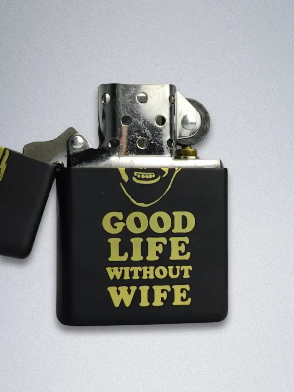 A matte black Zippo lighter with a gold graphic of a smiling, bearded man and the text "GOOD LIFE WITHOUT WIFE".